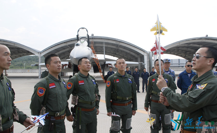 ↑艦載航空兵某部司令員戴明盟向飛行員演示空中飛行注意事項。